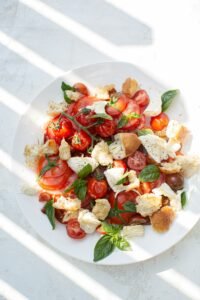 Caprese salade met burrata, rijpe tomaten, verse basilicum en groene pesto op een wit bord