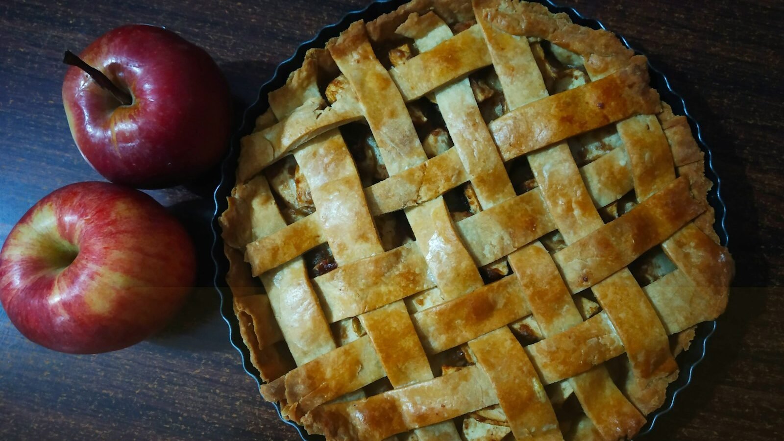 Klassieke appeltaart met deegruitjes en een verse appel ernaast