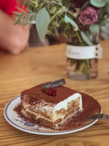 Portie tiramisu bestrooid met cacaopoeder, laagjes mascarponecrème en in koffie gedrenkte lange vingers zichtbaar
