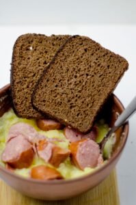 Kom stamppot met plakjes rookworst en roggebrood